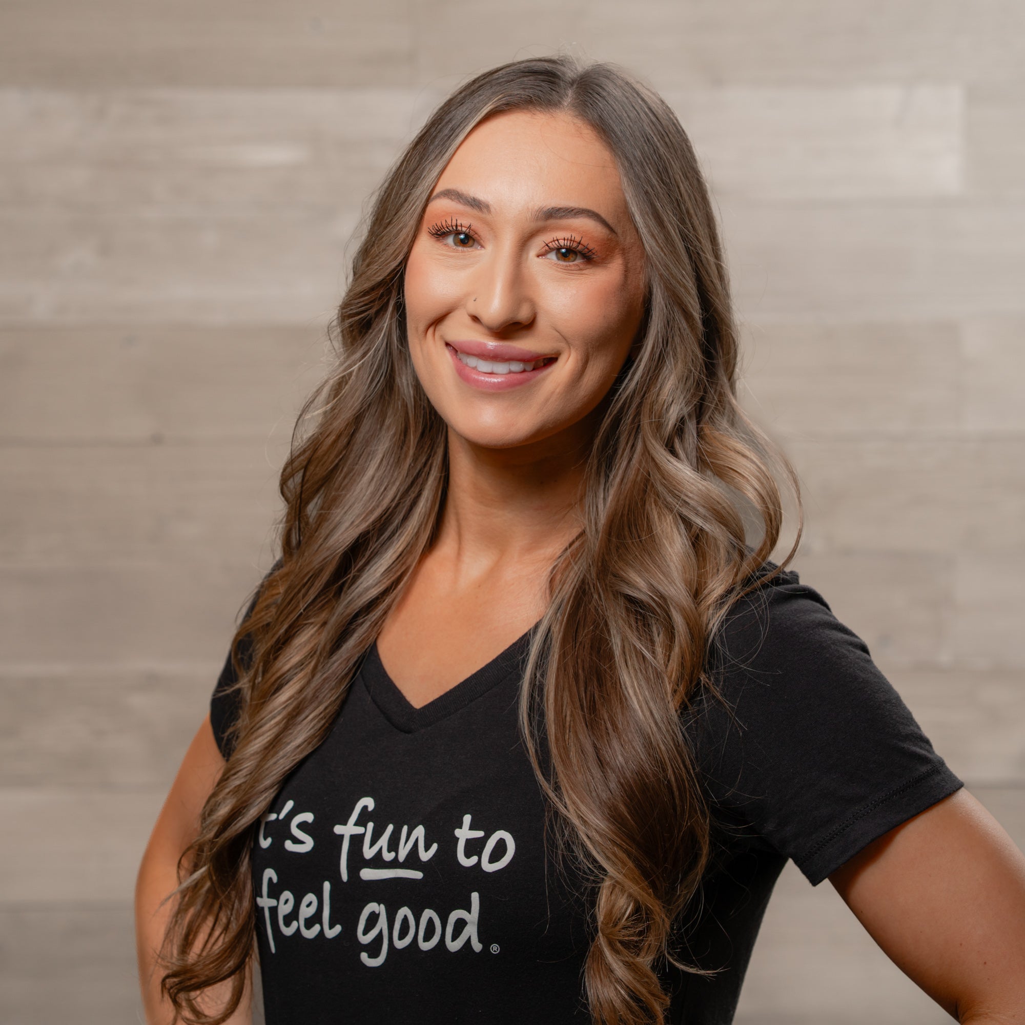 Woman wearing a black t-shirt with text, standing against a neutral background