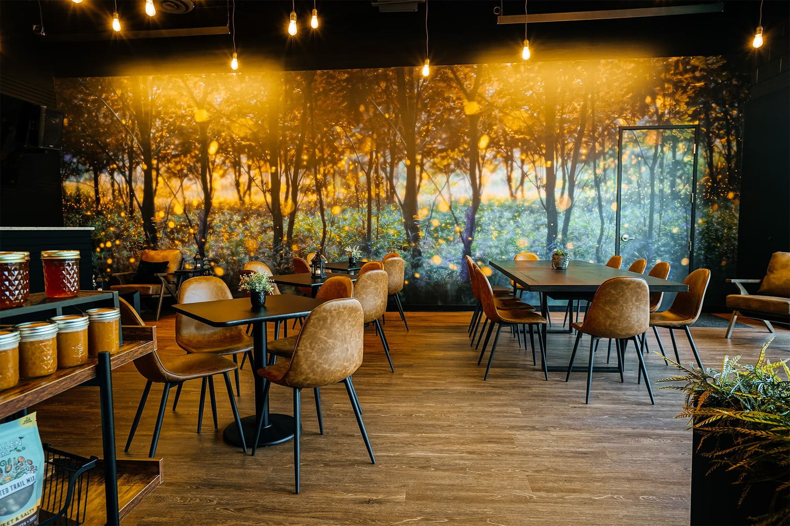 Dining area with wooden tables and chairs, wall mural of trees, and decorative elements.