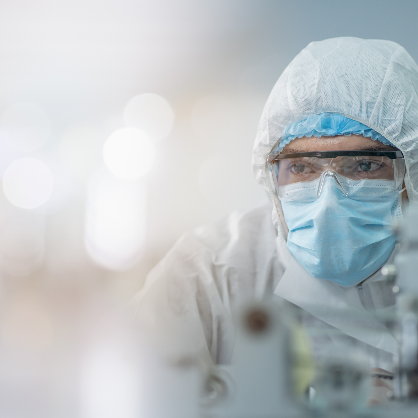 Person wearing a protective suit, mask, and goggles in a laboratory setting